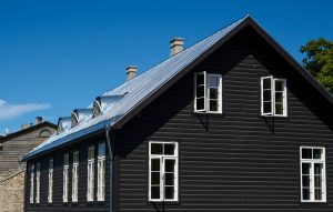 Black,Wooden,House,Under,A,Gray,Roof,Against,A,Blue